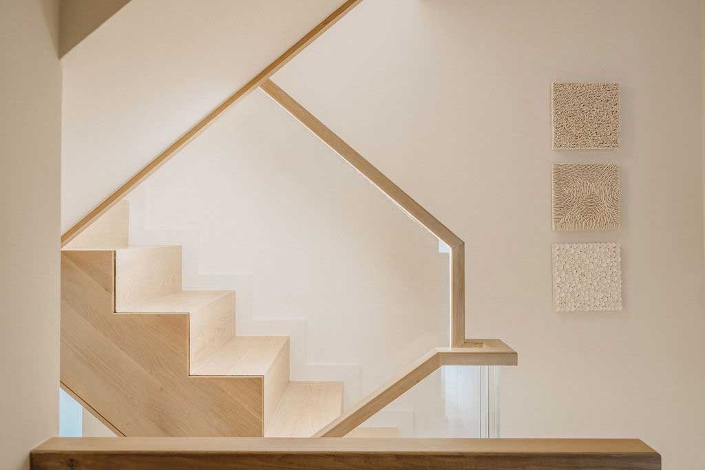  A staircase featuring wooden handrails and a transparent glass railing, showcasing a modern design aesthetic.  
