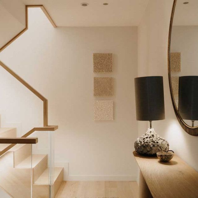 A modern staircase featuring a sleek mirror and a stylish lamp, enhancing the contemporary interior design.