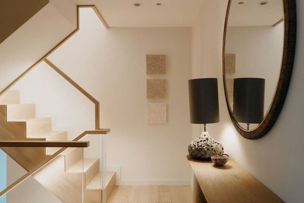 A modern staircase featuring a sleek mirror and a stylish lamp, enhancing the contemporary interior design.